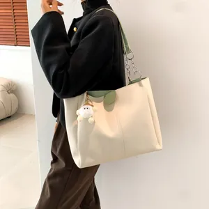 Minimalist cream and green tote bag with plush sheep charm shown on model in studio