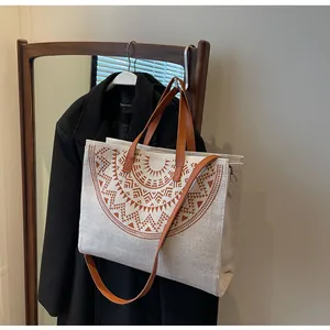 Detail of beige woven tote bag with brown geometric patterns in a natural indoor setting