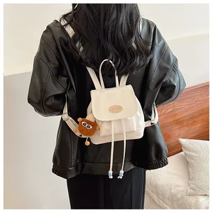 Detail of white mini backpack with drawstrings and brown plush bear charm on back