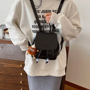 Minimalist black leather mini backpack for women with a cute plush charm and fashion logo