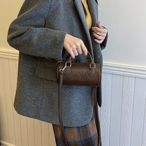 Borsa a mano a botte marrone minimalista con dettagli argento e tracolla in stile street