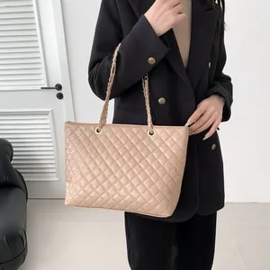 Beige quilted tote bag with metal chain strap worn with a black blazer for office style