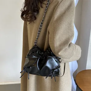 Retro Eimertasche aus schwarzem Leder mit Falten und Schleifen an einer Metallkettenriemen
