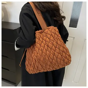 Detail of a brown quilted tote bag with bubble lattice texture and wide shoulder strap