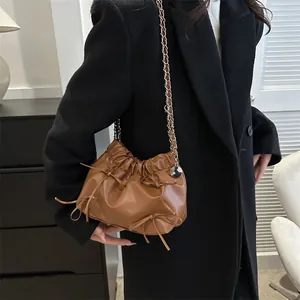 Vintage-Eimertasche in Braun mit Schleifen und Kettenriemen in Lifestyle-Umgebung