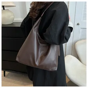 Chocolate brown faux leather Hobo bag shown on shoulder in a minimalist indoor setting