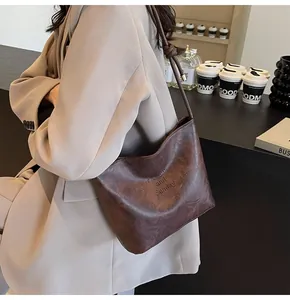 Détail d'un sac hobo en cuir marron foncé avec bandoulière nouée et motif embossé