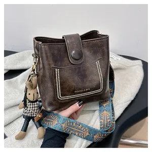 Detail of vintage brown bucket bag featuring folk jacquard wide strap and rabbit charm