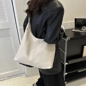 Minimalist beige oversized faux leather tote bag with wide strap for urban commuting