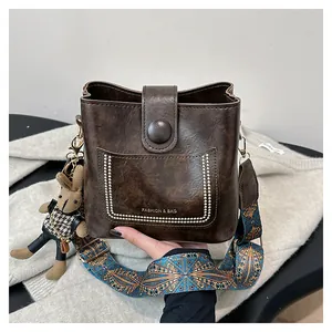 Detailed close-up of dark brown bucket bag with embroidered strap and cute rabbit charm