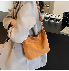 Sac hobo en daim marron caramel porté avec un blazer gris pour un look urbain chic
