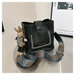 Detail of black bucket bag with gold rivets and ethnic style pattern wide shoulder strap