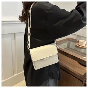 Dettaglio di una borsa a tracolla minimalista in ecopelle bianco crema con catena