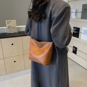 Sac seau minimaliste en cuir marron avec texte gaufré pour un style décontracté