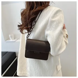 Dettaglio di una borsa a tracolla marrone scuro con finitura opaca e catena elegante
