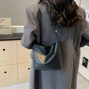 Sac seau minimaliste en cuir noir avec lettrage tendance et bandoulière à nœuds