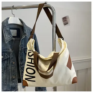 Detail of canvas tote bag with brown leather accents and black FASHION lettering print