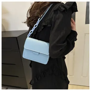 Dettaglio borsa a tracolla azzurra con elegante catena in plastica indossata da una modella