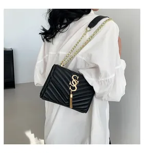 Detail of black quilted shoulder bag featuring gold chain strap and tassel ornament
