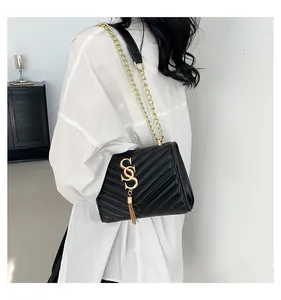 Detail of black quilted shoulder bag featuring gold V-stitch and metallic tassel logo