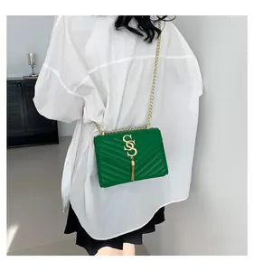 Detail of green quilted crossbody bag with golden S buckle and fringe tassel detail