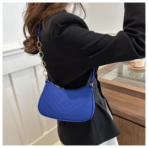 Detailed shot of blue crescent shoulder bag with V-shaped quilting and gold chain strap
