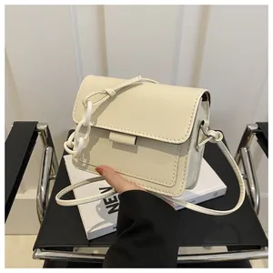 Dettaglio della borsa a tracolla crema minimalista con catena decorativa bianca spessa