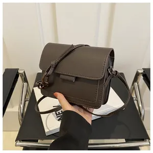 Dettaglio di una borsa a tracolla marrone scuro con finitura opaca e maglie in resina