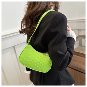 Detail of neon green crossbody bag with V-shaped quilting and gold zipper accents