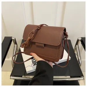 Dettaglio di borsa a tracolla in pelle marrone con catena decorativa e cuciture su sedile