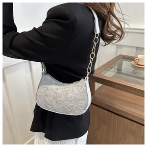 Gray felt underarm bag with V-shaped quilting and gold chain detail on model