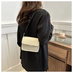 Close-up of minimalist cream white shoulder bag with black strap and fine stitching