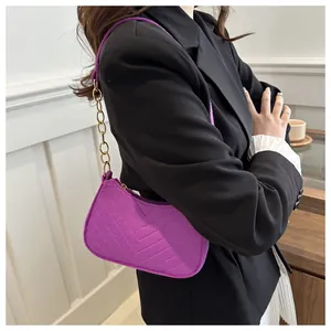 Detailed shot of a purple quilted shoulder bag with gold chain strap on a model