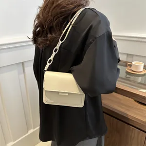 Borsa a tracolla crema minimalista con catena in resina mostrata su modella con stile