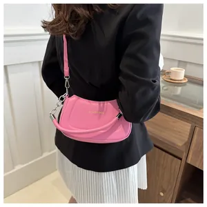 Sac à bandoulière rose en demi-lune avec texte doré et chaîne porté par un mannequin