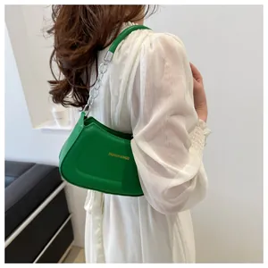Détail du sac à bandoulière croissant vert avec chaîne en métal et logo décoratif