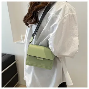 Detail of light green minimalist leather crossbody bag with a wide black shoulder strap