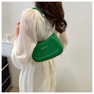 Détail du sac bandoulière croissant vert avec logo doré et chaîne argentée