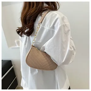 Detail of khaki baguette shoulder bag featuring V-shaped quilting and gold chain strap