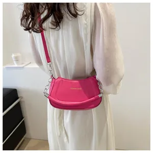 Détail du sac à bandoulière demi-lune rose flamant avec chaîne argentée et logo doré