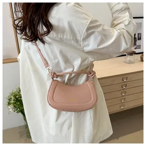 Detail of pink half-moon crossbody bag with knotted handle and golden fashion logo
