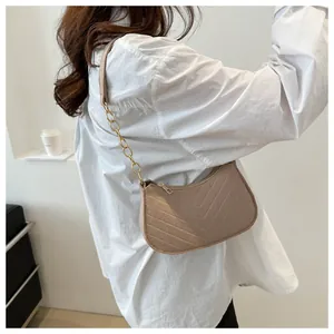 Side view of a light brown V-quilted shoulder bag with gold chain strap on a white shirt