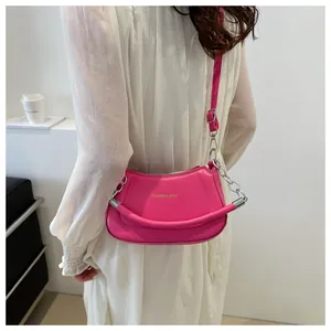 Détail d'un sac à bandoulière rose vif matelassé avec une poignée rembourrée et une chaîne