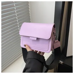 Close-up of light purple flap shoulder bag with black wide strap and metal hooks