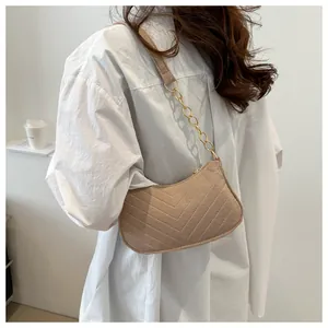 Detail of camel plush crossbody bag with V-quilted stitching and gold chain strap