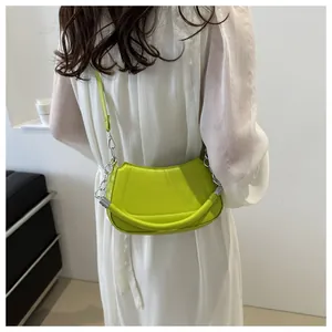 Détail du sac à bandoulière croissant vert fluo avec chaîne argentée sur modèle