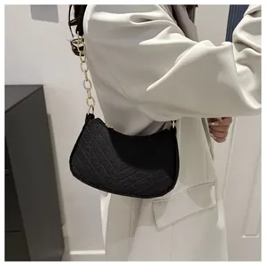 Detail of black V-quilted hobo bag with gold chain strap on a grey blazer outfit