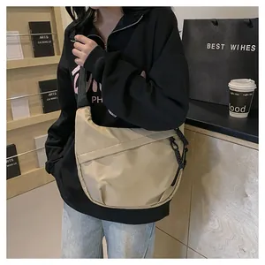Close-up of khaki nylon tote bag with wide strap and zipper detail in casual setting