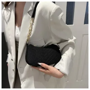 Close-up of black tweed crossbody bag with gold chain strap on model's shoulder