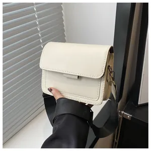 Detail of a creamy white PU leather crossbody bag with a wide black nylon shoulder strap
